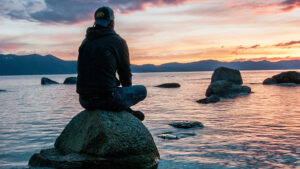 A contemplative man sits on a rock; Keegan Houser / Unsplash