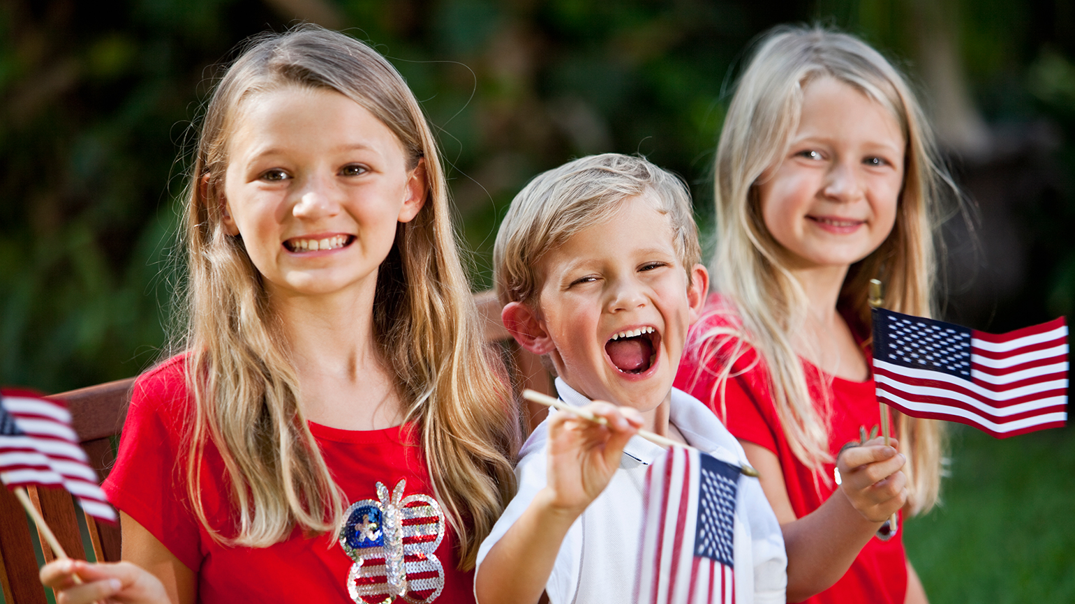 Joyful kids wave American flags on the 4th of July; kali9 / Getty Images