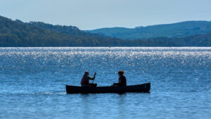 A guy and girl canoe on the lake as the sun sets.: iStock Editorial / Getty Images Plus