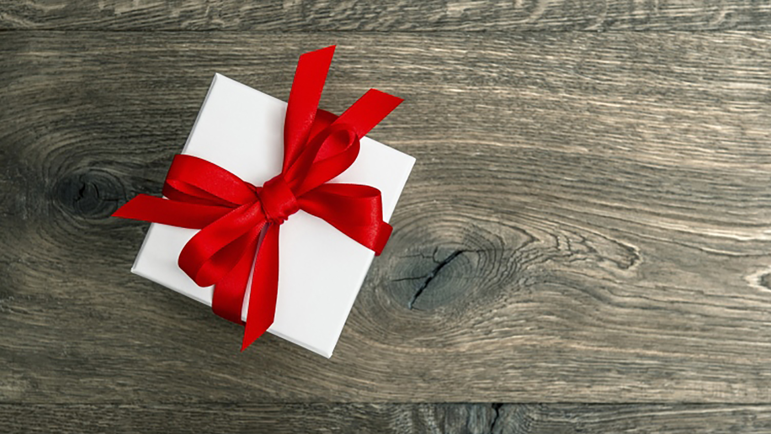 A white gift box with a red bow and ribbon; LiliGraphie / Getty Images