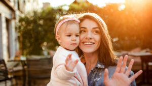 Young mom and baby daughter waving