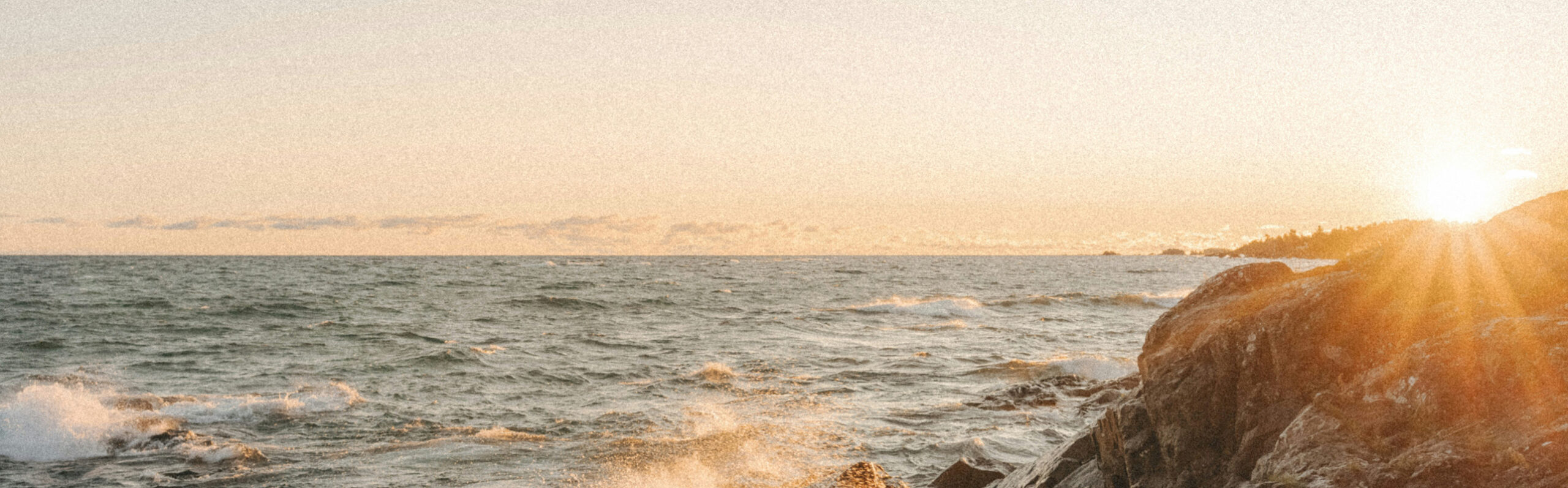Waves spray up the rocks as the sun rises.