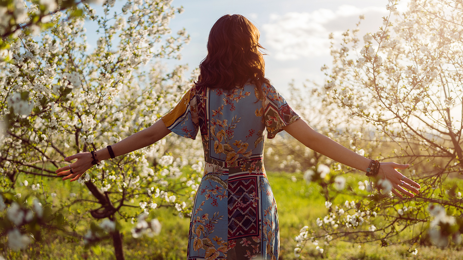 A woman stands, arms outstretched