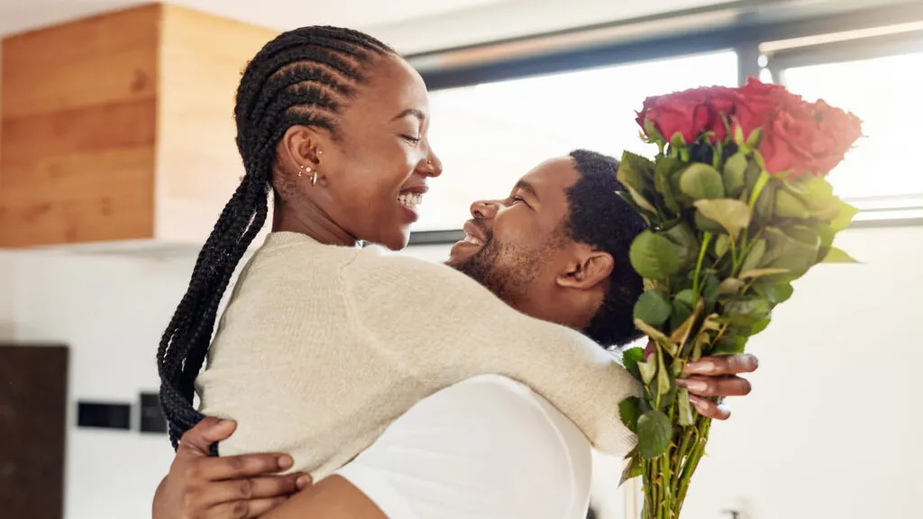 Young couple hugging and celebrating Valentine's day with flowers and devotionals