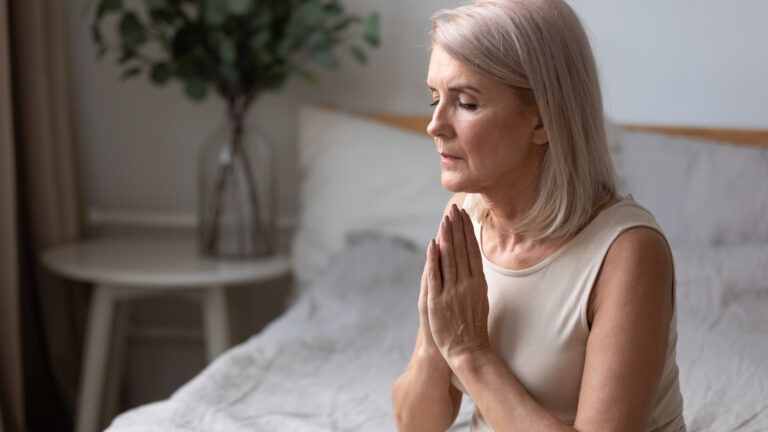 Woman sitting in bed and saying her morning prayer habit