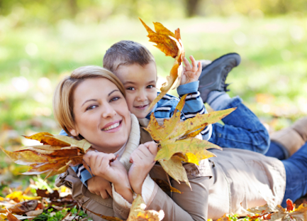 woman and son enjoying fall leaves
