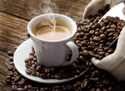 A steaming cup of coffee surrounded by coffee beans