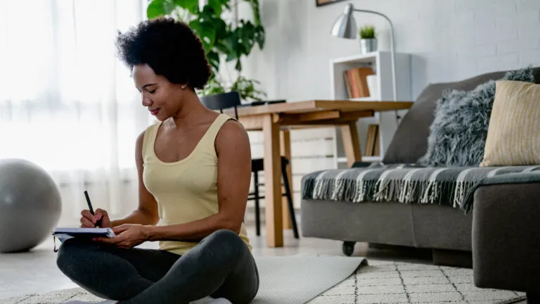 Woman writing down what she's giving up for lent in her journal