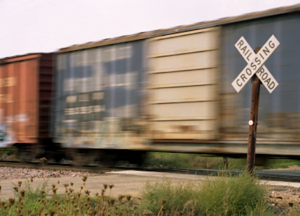 Boxcars traveling through a railroad crossing.