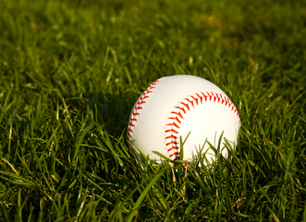 A baseball lying in the grass.