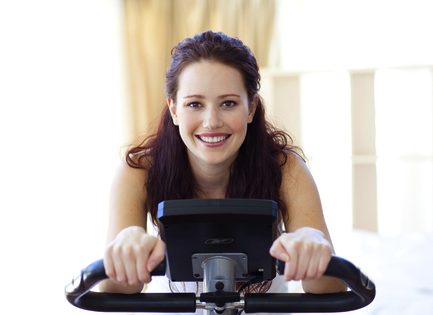 Woman exercising and praying on a stationary bike.