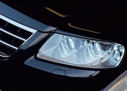 A photograph of a black car's sleek, shiny hood and headlight