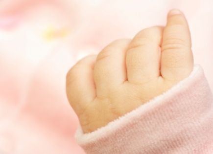Tiny precious newborn hand with pink sleeper