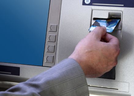 A man inserts his bank card into an ATM