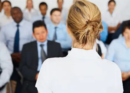 A woman, viewed from behind, addressing a group of people