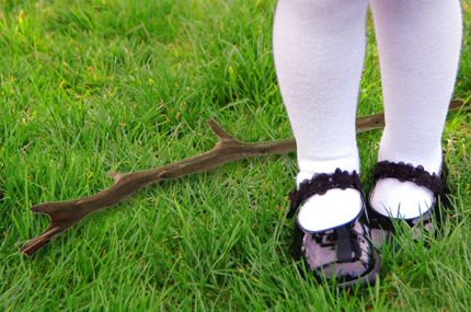 A closeup of a young girl's feet, with a dropped stick lying in the grass