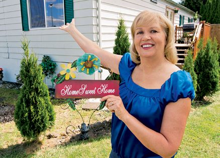 Barbara McCourtney stands proudly outside her home