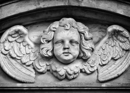 An angel in the architecture on the facade of a city building.
