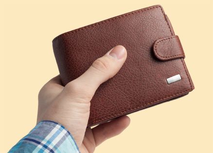 A closeup of a man's hand proffering a brown wallet