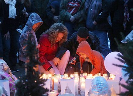 Mourners gather to pray and light candles in the darkness