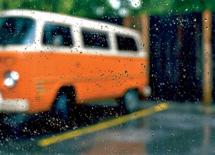 A parked orange VW van on a cold, rainy day