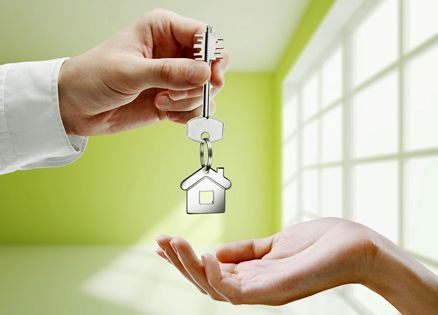 A man hands apartment keys to a woman.