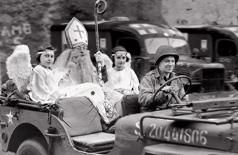 Richard Brookins as St. Nicholas arrives in a jeep accompanied by two angels