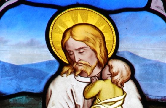 Stained glass of Jesus comforting a child
