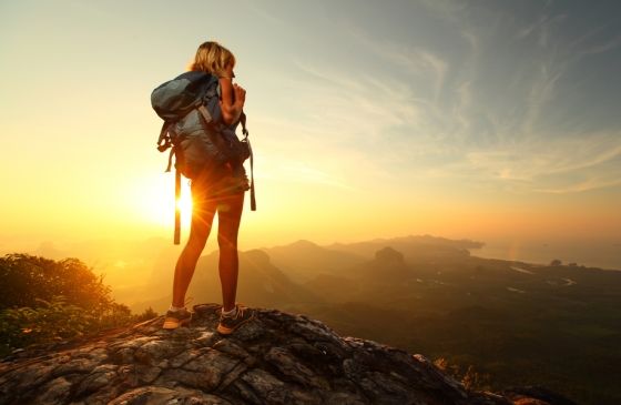 Woman on top of a mountain looking at the sunrise.
