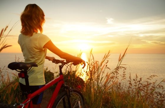 woman on bicycle thoughtfully taking in the sunrise
