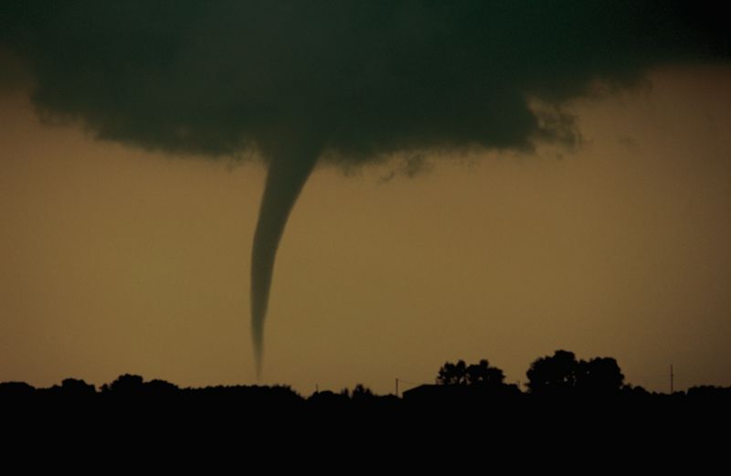 A funnel cloud dips down from dark, stormy clouds.