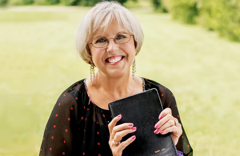 Mary Lou Carney, clasping a Bible