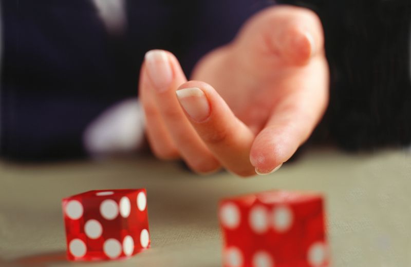 A hand rolling a pair of red dice