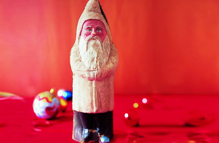 A wooden figure of old saint nick with a red background
