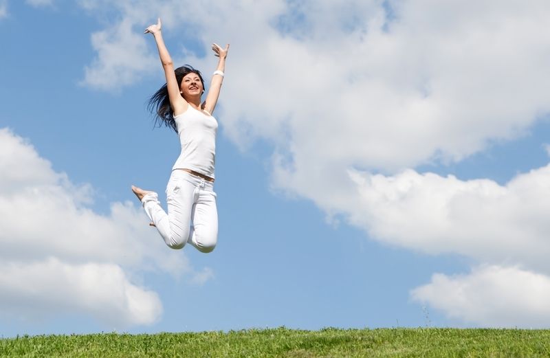 woman jumping for joy against a blue sky