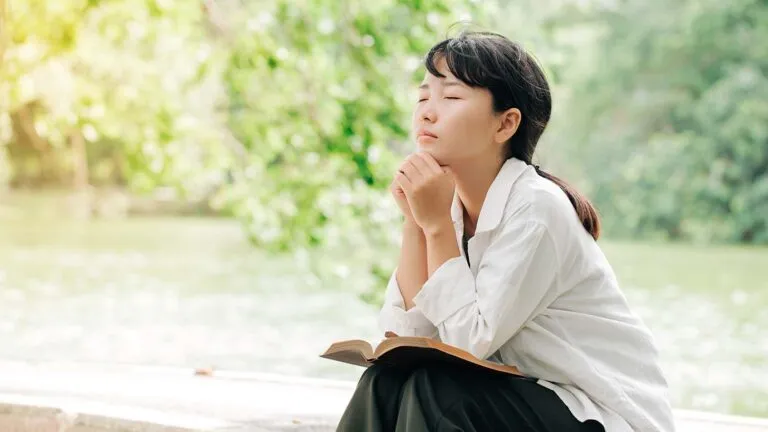 Woman outside praying about the message of Easter with her Bible