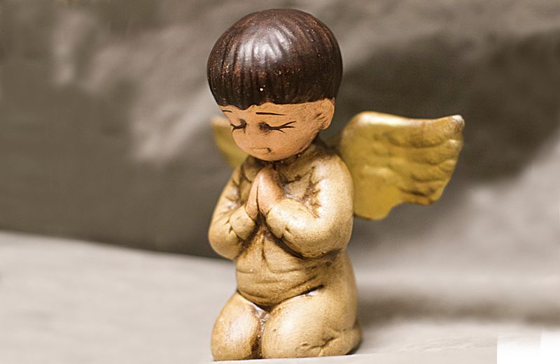 A ceramic angel with mocha-colored skin and cropped brown hair