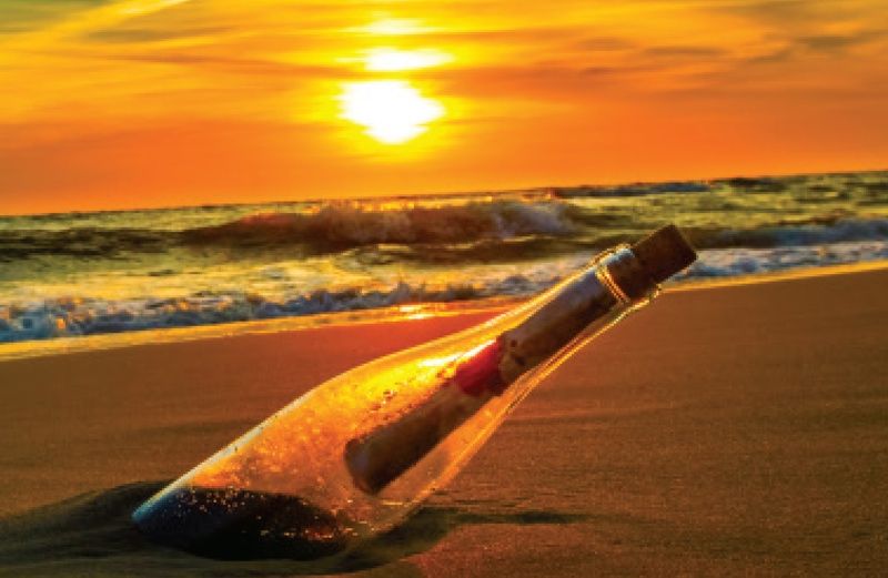A message in a bottle stuck in the sand near the ocean
