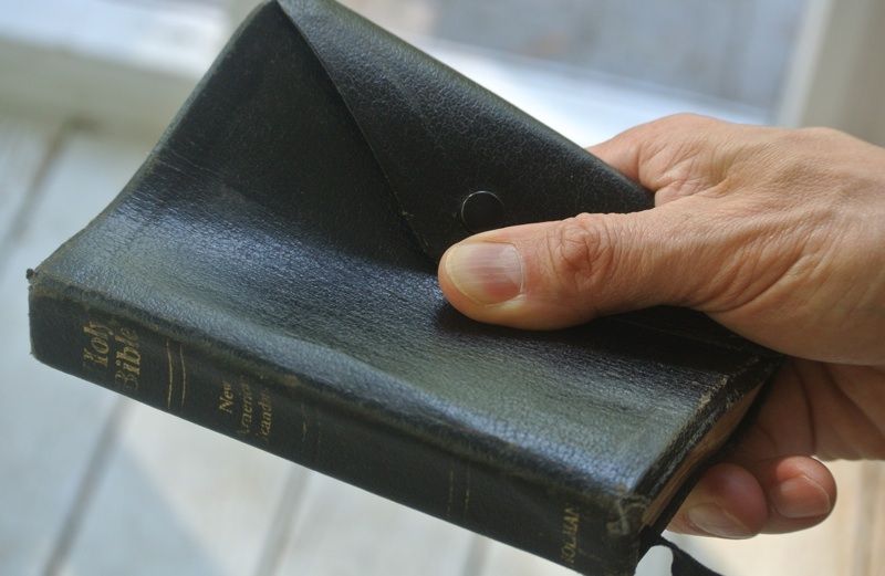 A well-worn Bible held on someone's hand