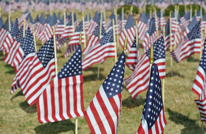 A field of American flags on a green lawn