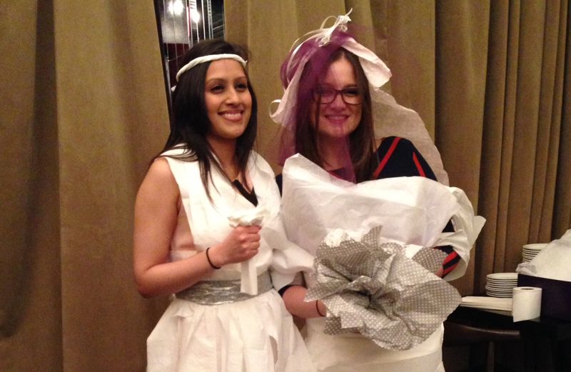 Two young women wearing toilet paper wedding dresses at a bridal shower