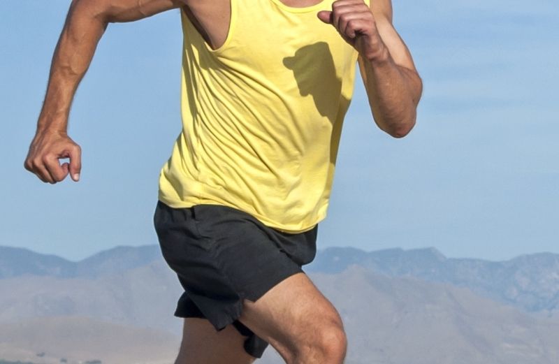 close-up of a man in a tank top and running shorts.