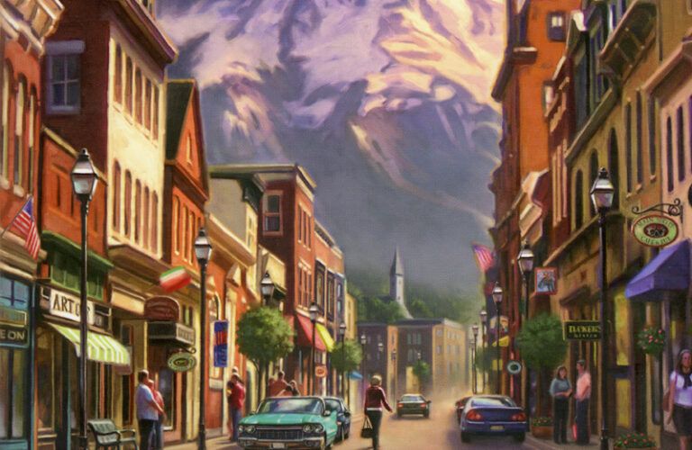 The main street of a small town with a mountain towering in the distance