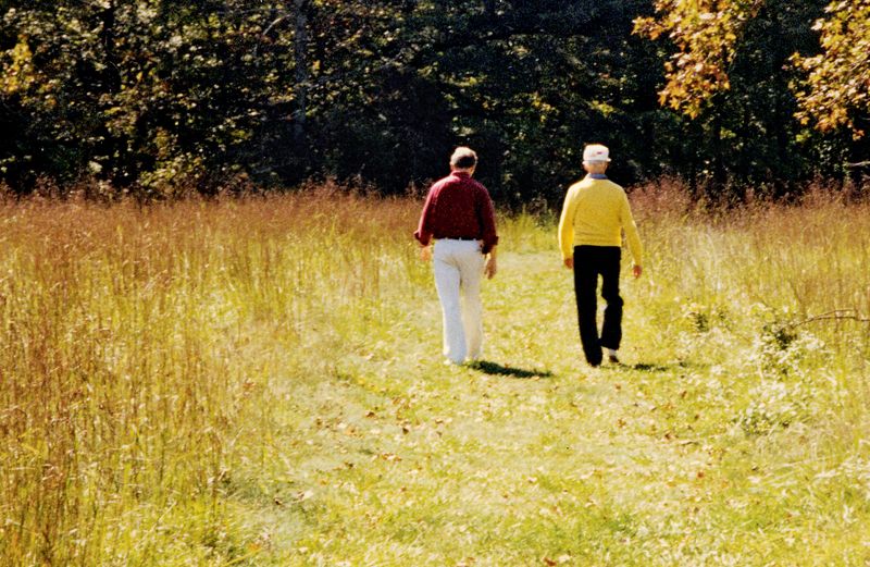 Grant (left) and his father stroll together through a sun-drenched meadow.