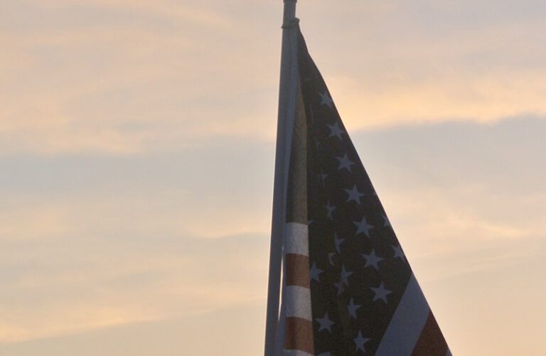 An American flag on a pole against a sky at sunset