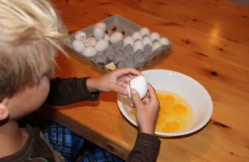 Shawnelle's son cracks eggs into a bowl.