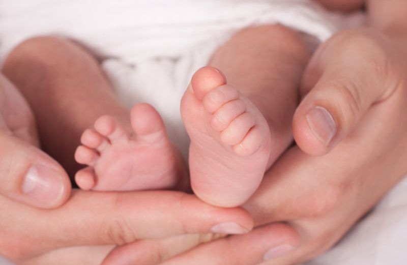 newborn baby feet lovingly cradeled in a parent's hands