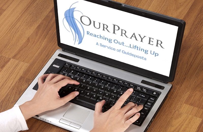 A woman's hands at a laptop keyboard, logging into OurPrayer.org