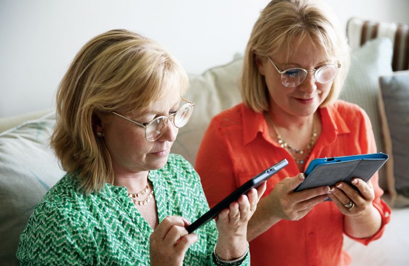 Karen (right) and Sharon in their new glasses, reading from tablets