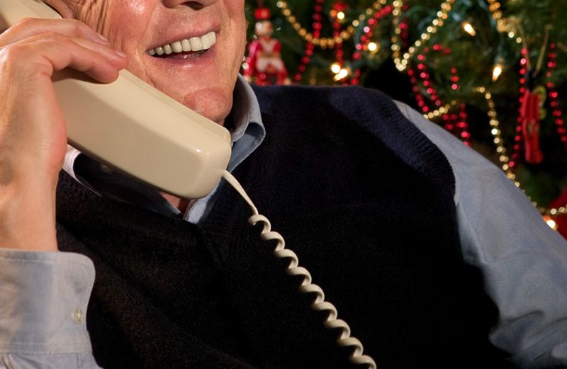 A man takes a Christmas phone call with a smile.